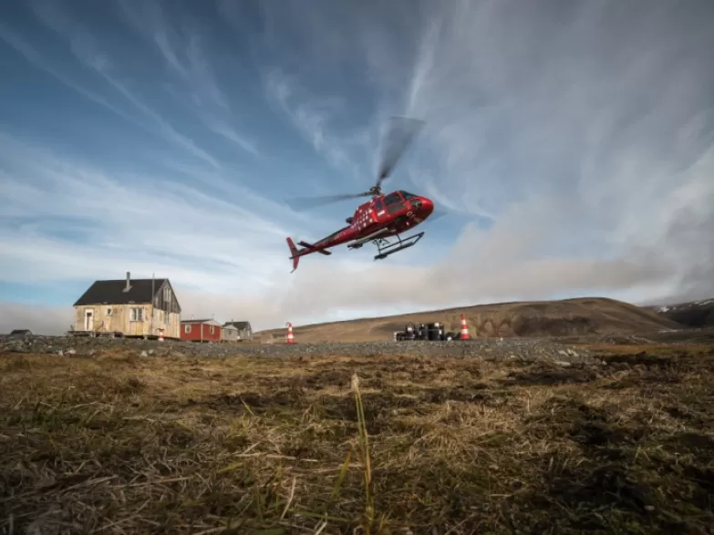 Red helicopter taking off in remote location